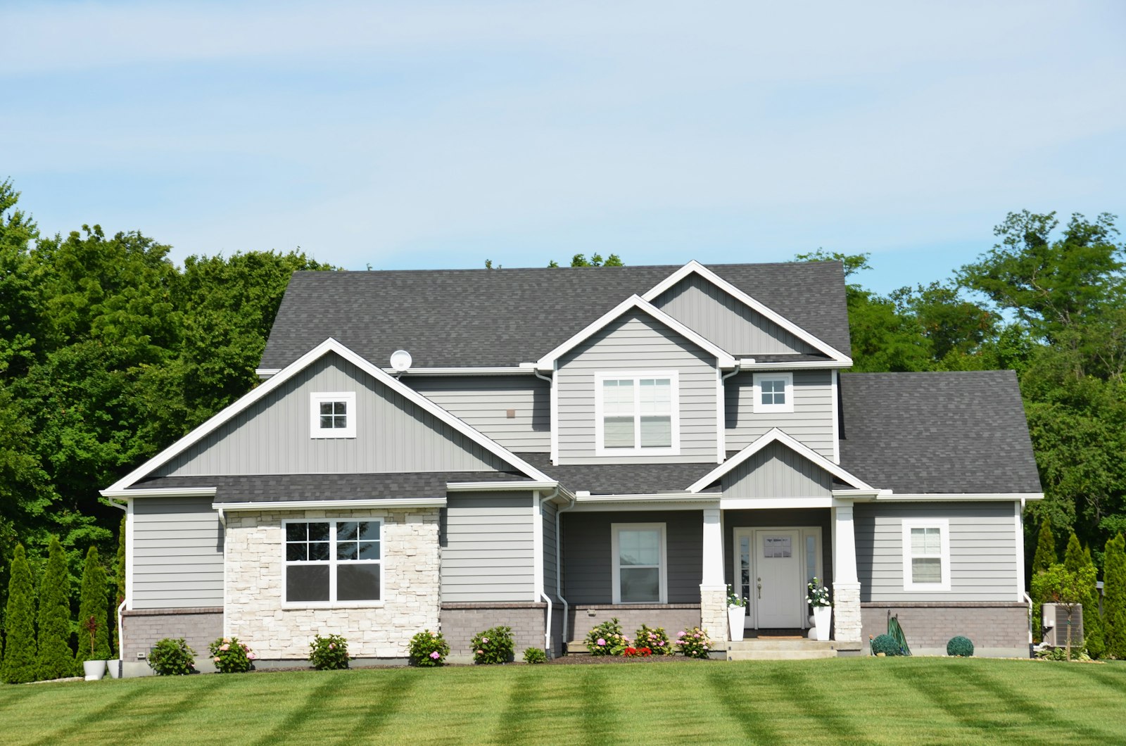 Two story gray home with white fascia and soffit lining the rooflines of its front gables
